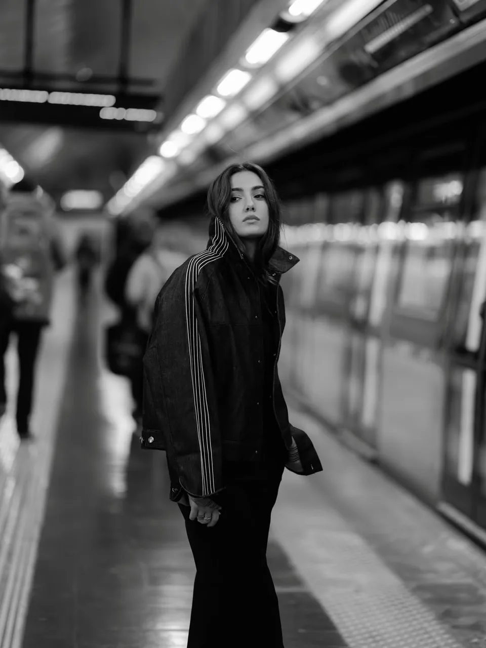 A black and white portrait of Zeudi looking up on a station platform.