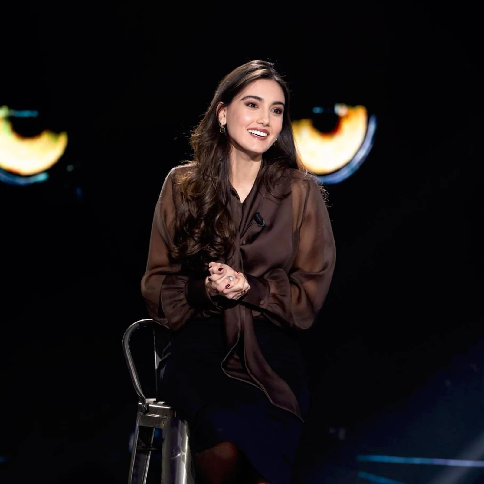 Zeudi Di Palma seated on the Belve interview set, wearing a brown blouse.