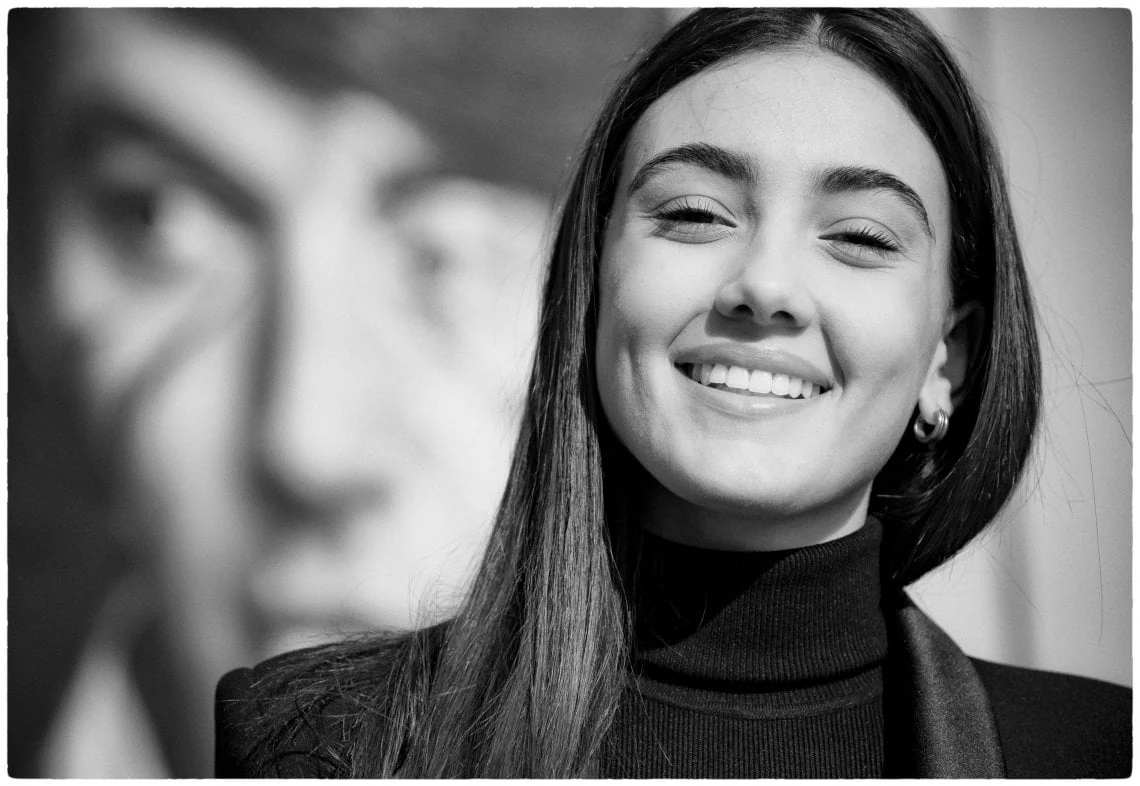 Black-and-white 2022 portrait of Zeudi Di Palma smiling in a black turtleneck and blazer.